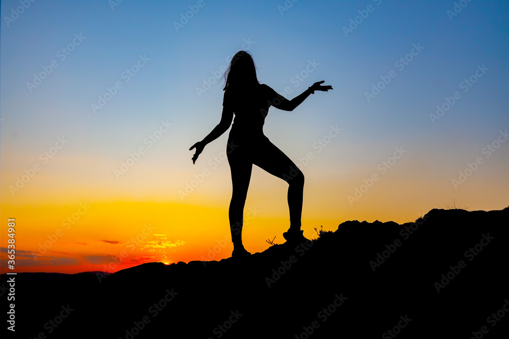 Silhouette of carefree woman at sunset
