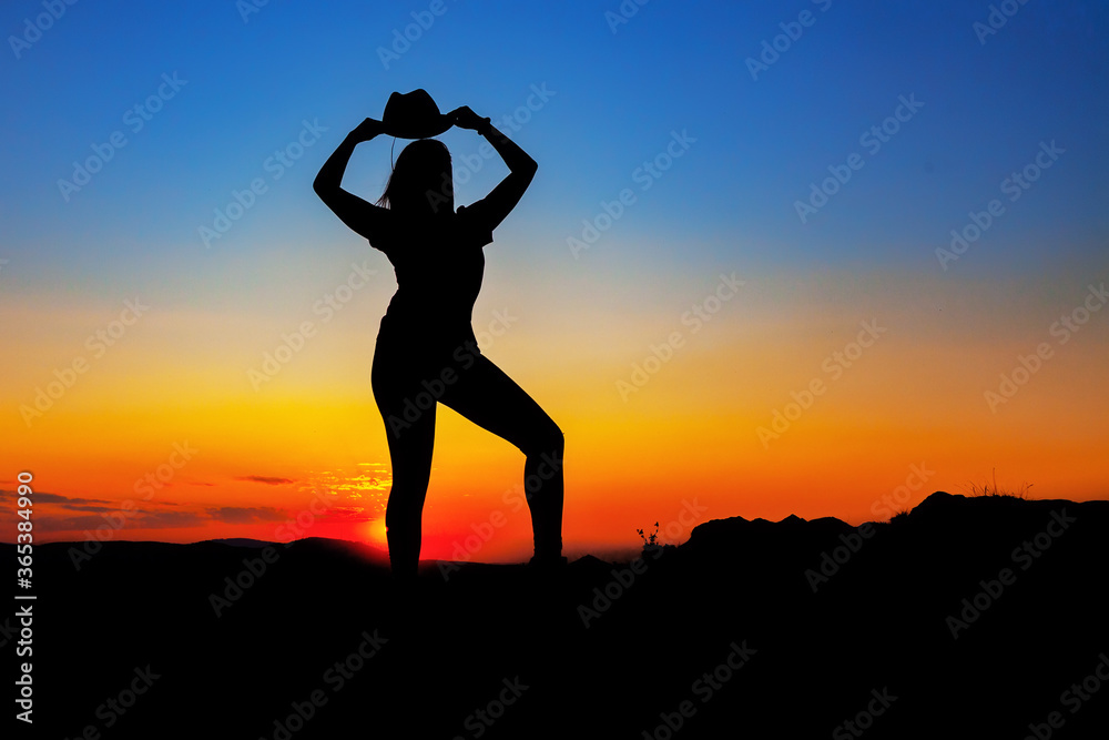 Silhouette of a woman in a hat at sunset