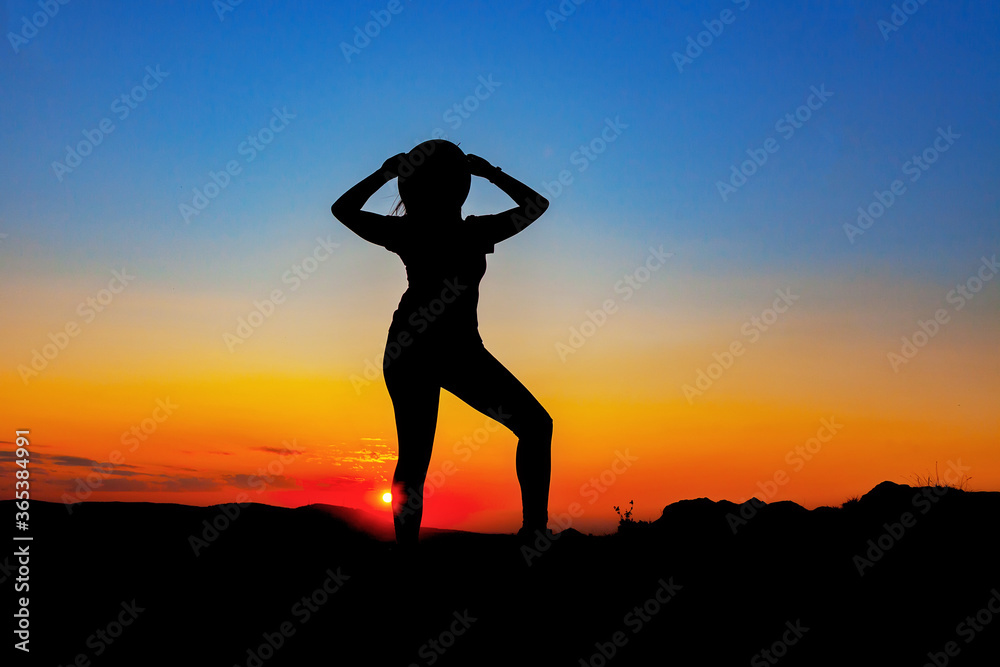 Silhouette of a woman in a hat at sunset