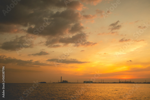 Sunset or sunrise sky and beach with industrial Estate in background. © ant