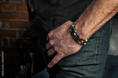 Elegant bracelets made of natural stones and minerals on a courageous hand. Close-up, on a brick wall background.