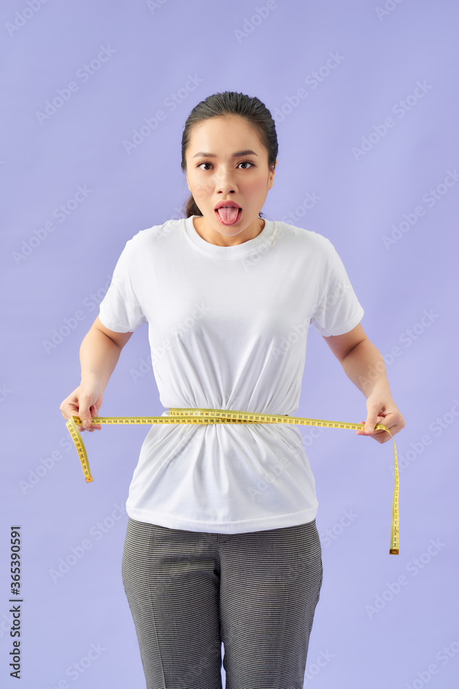Fototapeta premium woman unhappy with her body, the diet, the body measures the isolated violet background