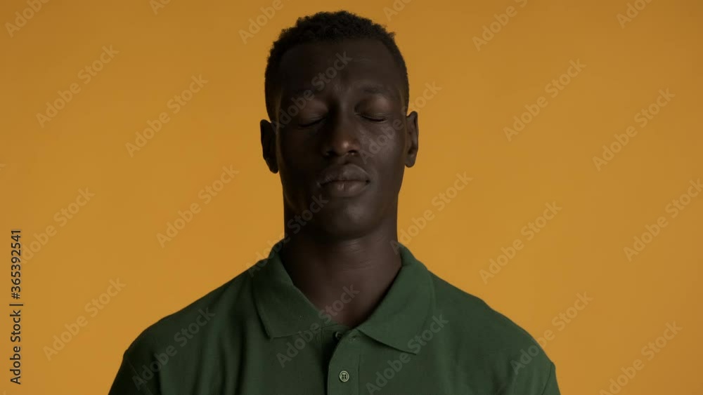 Young serious African American man tiredly posing on camera over colorful background. Weary expression Young serious African American man tiredly posing on camera over colorful background. Weary expression