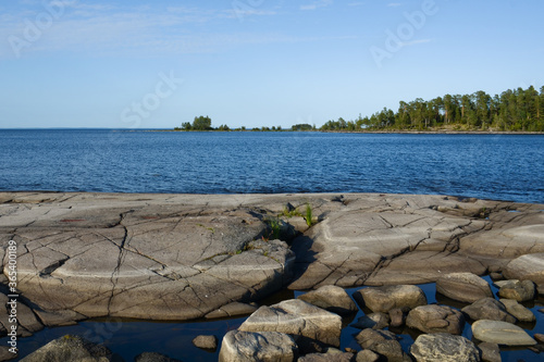 Clear sky, blue water and stones from gabbro diabase on shores of Lake Ladoga. photo