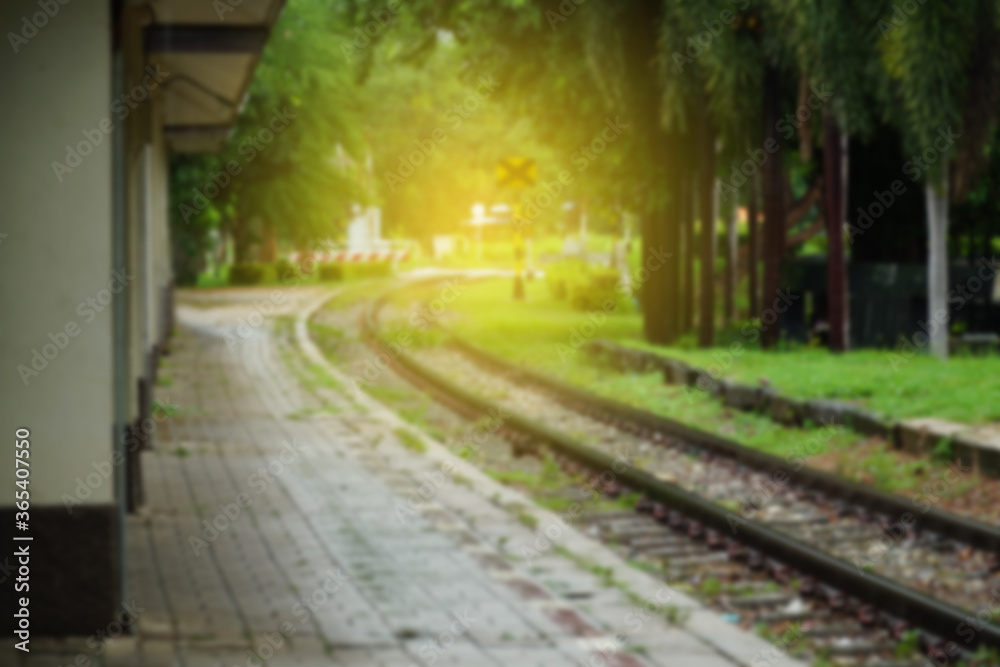 Blurred image of empty railroad track going into the light. Railway tracks with sleepers with platform in the rural station.
