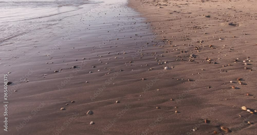 Walking forward along shore line of sandy beach in summer, looking down towards ground. Smooth, stabilized gimbal shot, low angle close to ground. Walking forward along shore line of sandy beach in summer, looking down towards ground. Smooth, stabilized gimbal shot, low angle close to ground.