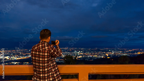 Fototapeta Naklejka Na Ścianę i Meble -  The man who is taking pictures of the scenery with the back view at night