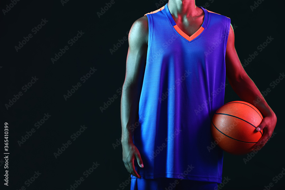 Young African-American basketball player on dark background Young African-American basketball player on dark background