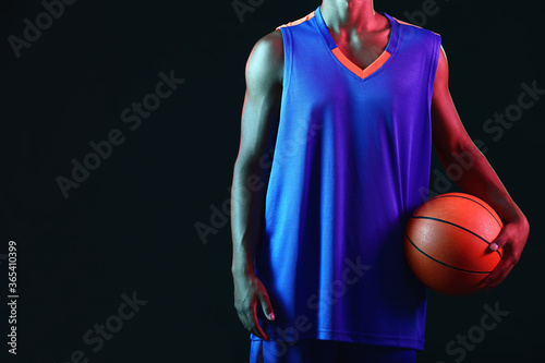 Young African-American basketball player on dark background