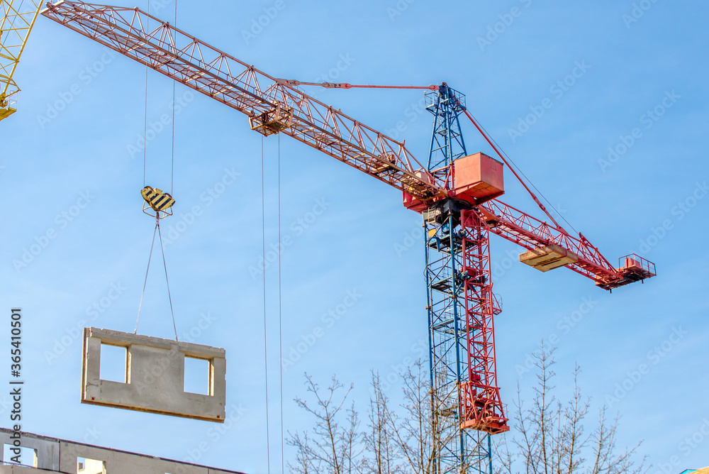 A construction crane lifts a concrete block A construction crane lifts a concrete block