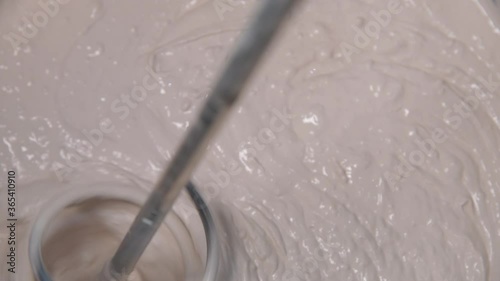 Slow motion pan shot of mixing concrete plaster with electric mixer. spatula and bucket with mortar on the construction site.