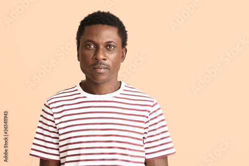 Sad African-American man on color background. Stop racism