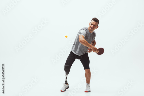 Athlete with disabilities or amputee isolated on white studio background. Professional male table tennis player with leg prosthesis training in studio. Disabled sport and healthy lifestyle concept. © master1305