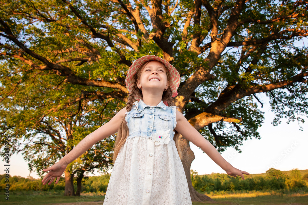 child and a huge tree in the forest. old oak and a little girl