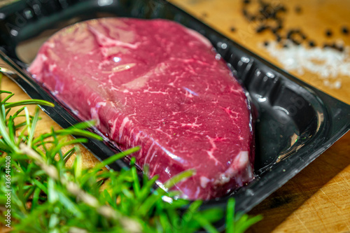 Beef steak in vacuum skin packaging and spices on wooden chopping board
