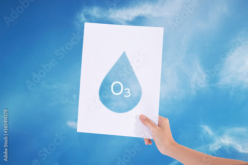 Female hands holding white paper with water drop in blue sky background./Ozone concept