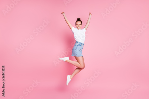 Full length profile photo of cute funky lady pretty bun summer weekend good mood jump high up flight celebrating wear white t-shirt mini skirt shoes isolated pink color background