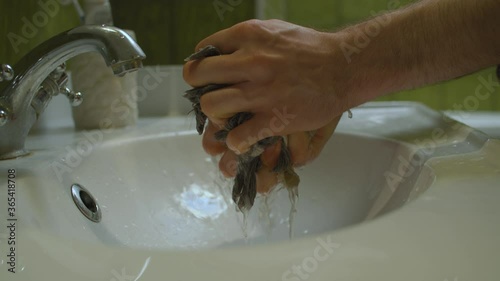 close up shoot mens hands squeezing floor mop in the sink in bathroom