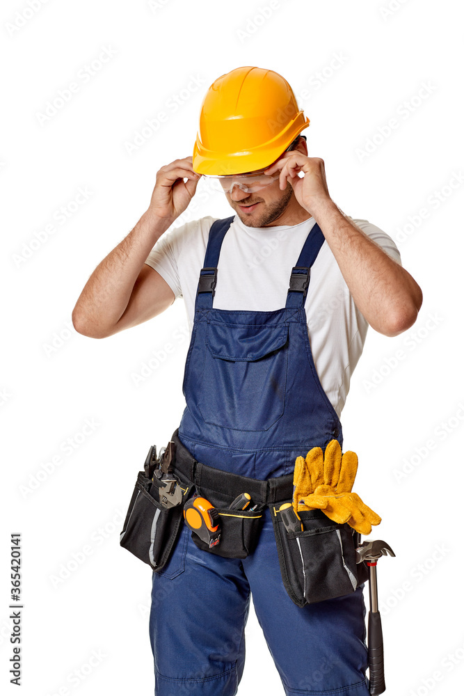Young caucasian repairman worker in yellow hard hat and uniform. handyman wearing tool belt and safety glasses isolated on white studio background Young caucasian repairman worker in yellow hard hat and uniform. handyman wearing tool belt and safety glasses isolated on white studio background