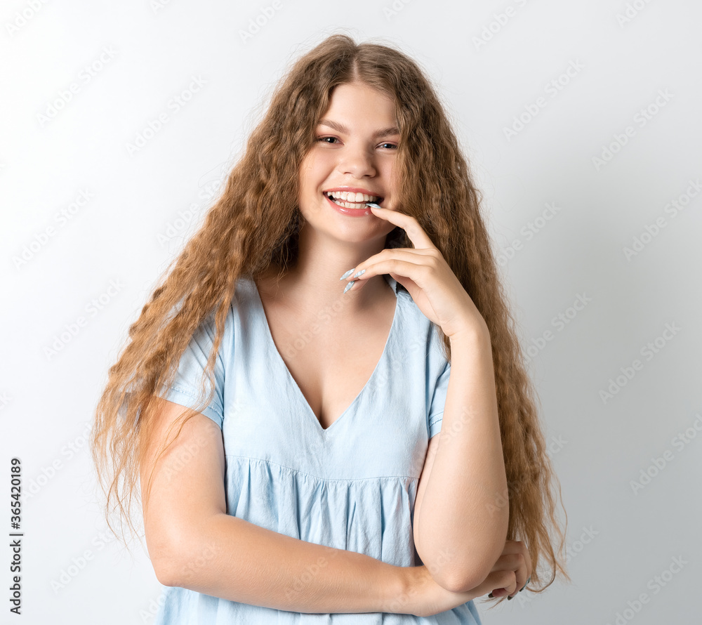 Photo of thoughtful European young woman with curly long hair looks with dreamy expression aside. Isolated over white background. Photo of thoughtful European young woman with curly long hair looks with dreamy expression aside. Isolated over white background.