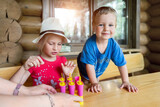 Two cute adorable caucasian blond little sibling sitting at table home yard and have fun tasting mom homemade fruit icecream. Young happy sister and brother enjoy laughing outside. Family love care
