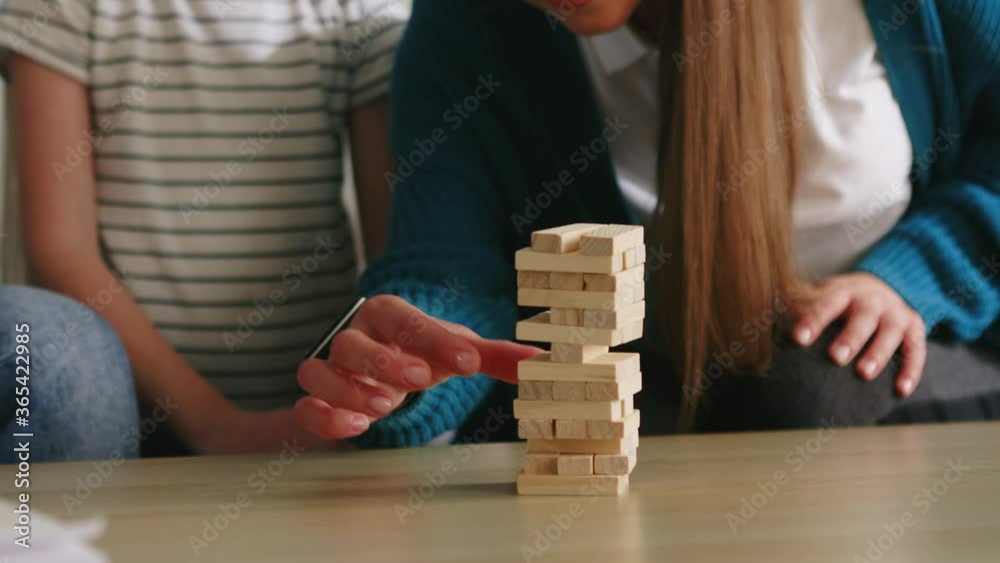 Young parents spend time with their small daughter, reducing stress and playing their favorite board game, jenga, family relationships concept, Foreground, Slow motion.