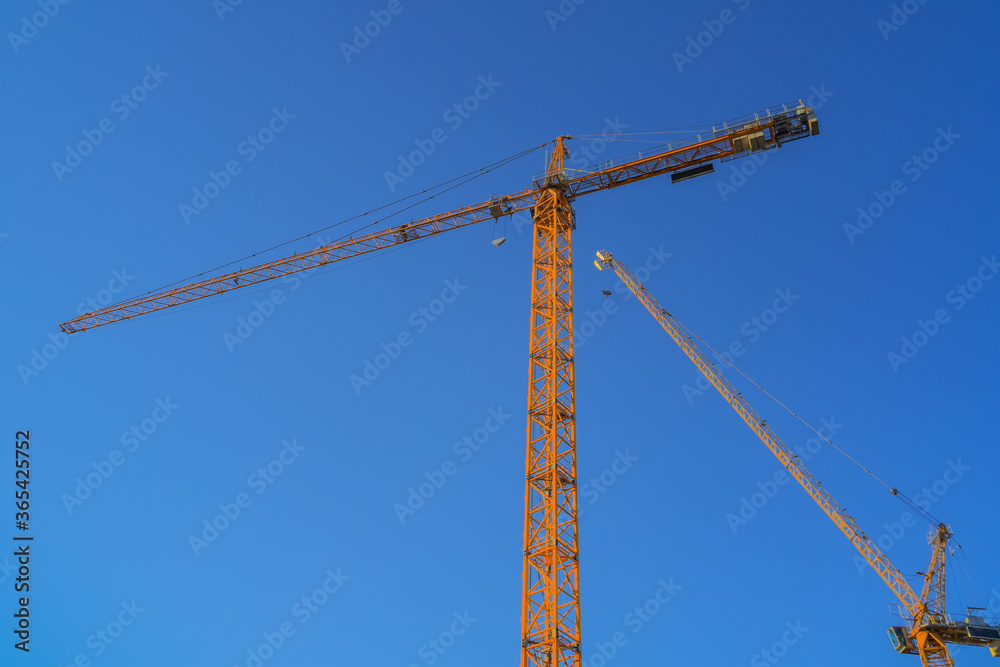 Tower cranes at building site against a blue sky in London