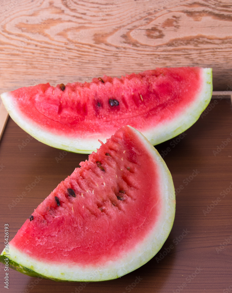 Two halves of a ripe red watermelon, on a wooden table Two halves of a ripe red watermelon, on a wooden table