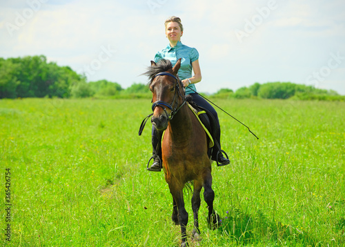 One Caucasian horsewoman is galloping through the field.