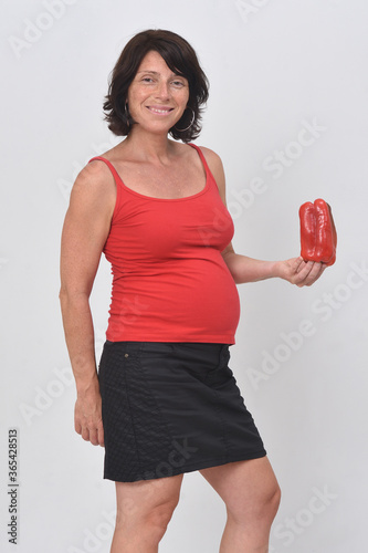 pregnant woman holding a red pepper on white background