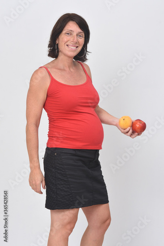 pregnant woman holding a plum on white background