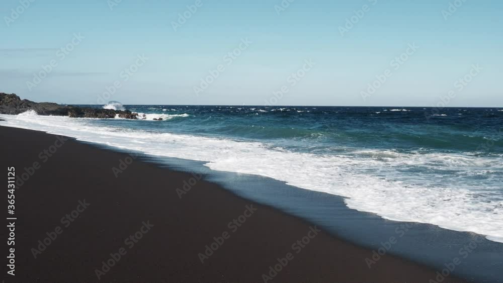 Wild beach with black volcanic sand on a sunny day. Wild beach with black volcanic sand on a sunny day.
