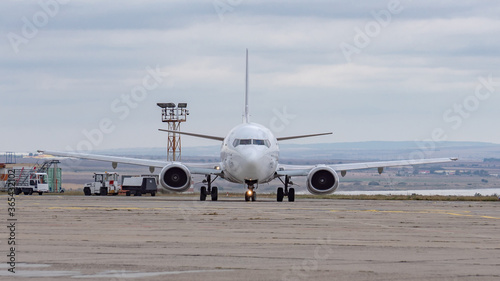 Front view of airplane. Commercial passenger jet airliner taxiing on airport apron, dynamic dark blue cloudy sky background. Modern technology in fast transportation, business travel, charter flights.