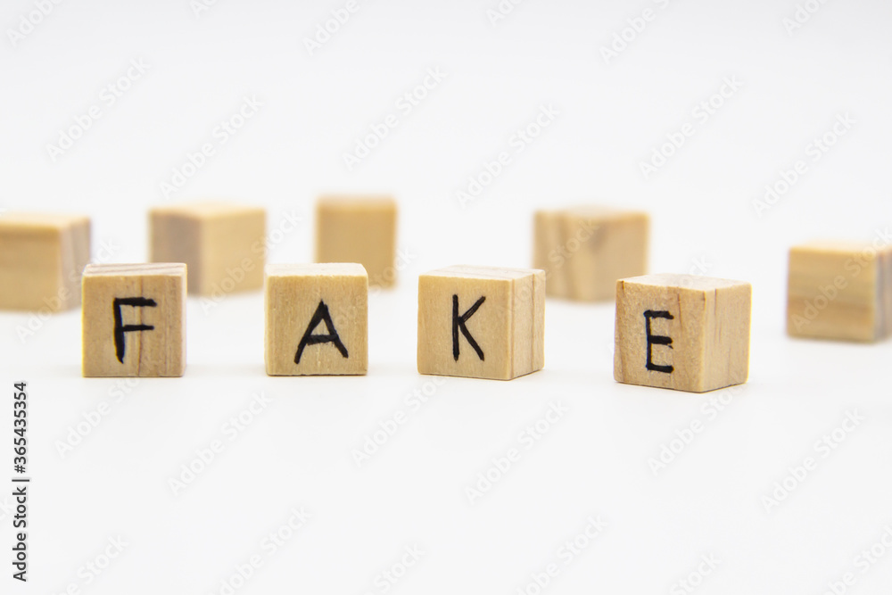 A word fake written on the wood cubes. Fake lettering made of wooden cubes isolated on white A word fake written on the wood cubes. Fake lettering made of wooden cubes isolated on white