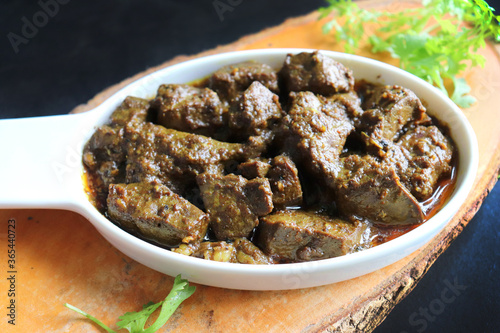 Mutton Liver Masala or goat Kaleji fry, garnished with coriander. Kaleji fry is a very tasty & popular Nonvegetarian Indian dish. Made from the goat liver. Over black background. copy space. 
