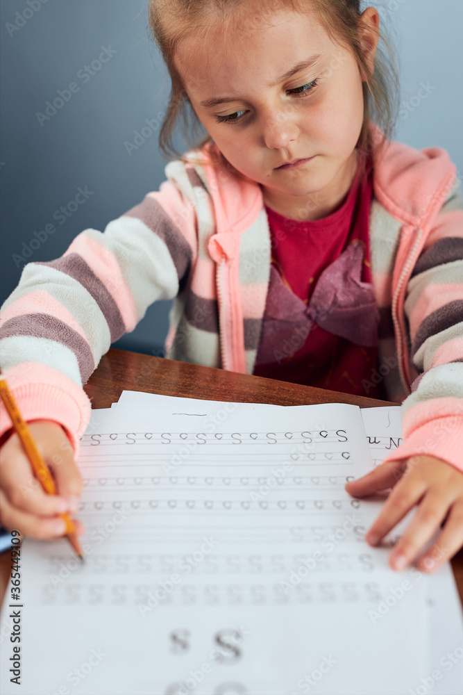 Little girl preschooler learning to write letters reluctantly. Kid writing letters, doing a school work unwillingly. Concept of early education Little girl preschooler learning to write letters reluctantly. Kid writing letters, doing a school work unwillingly. Concept of early education