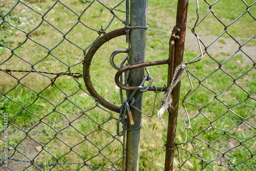 Large fence with wire mesh and barbed wire a chain and a padlock. Grassland, meadow construction site background