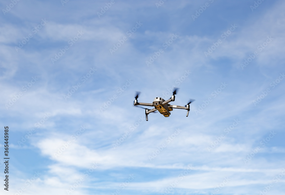 Quadcopter drone with digital camera in flight with blue sky background.. Quadcopter drone with digital camera in flight with blue sky background..