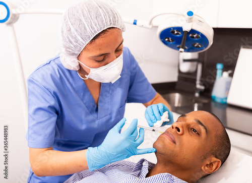 Latin american man getting injections for face skin tightening at aesthetic cosmetology clinic