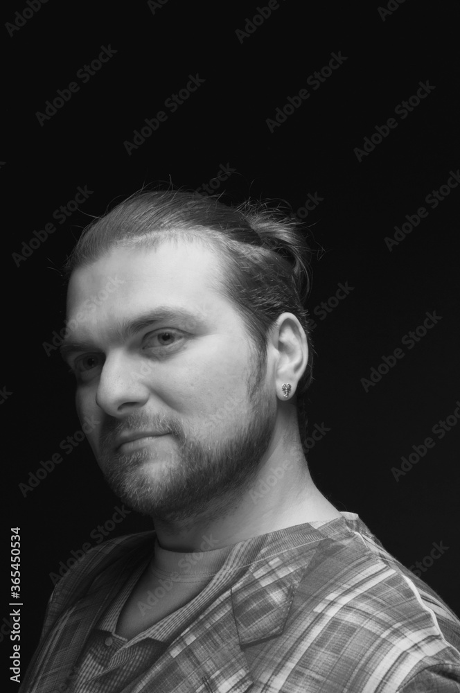 black and white portrait of stylish bearded man in checkered blazer with hair bun looking away black and white portrait of stylish bearded man in checkered blazer with hair bun looking away