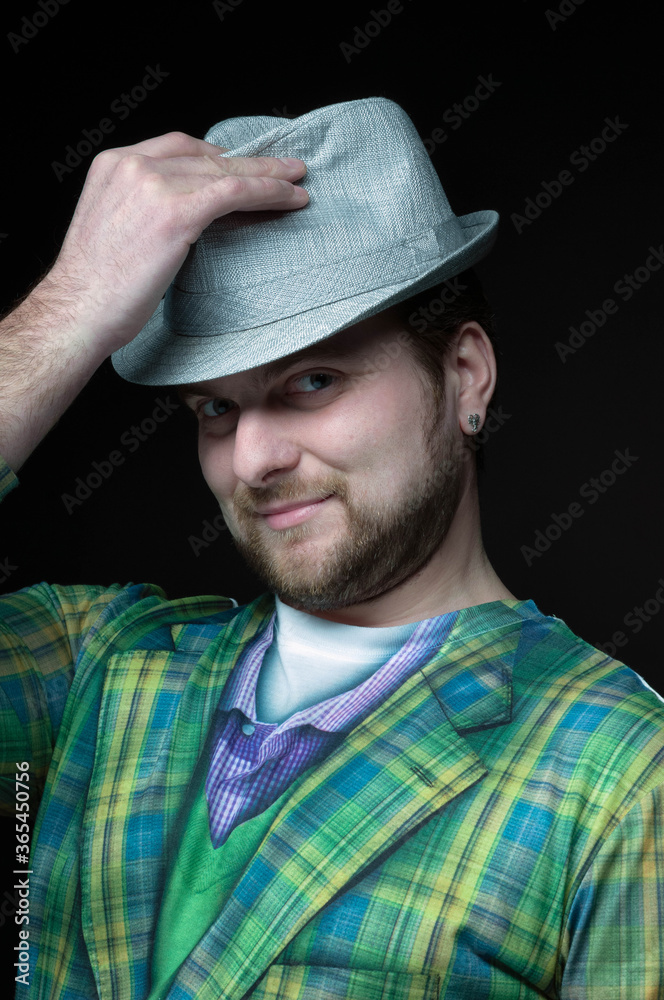low key portrait of handsome bearded man in green blazer putting on grey hat and looking at camera on black low key portrait of handsome bearded man in green blazer putting on grey hat and looking at camera on black
