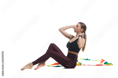 Young slim girl gymnast in sportswear is training with a multi-colored ribbon isolated on white background.