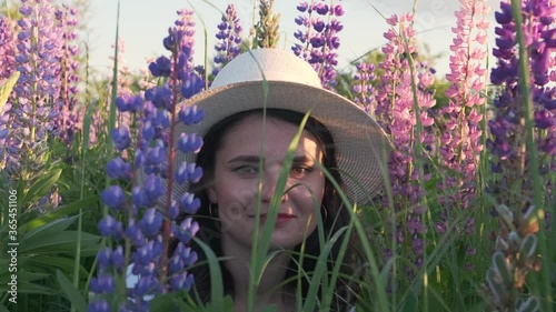 Portrait of a smiling woman in a hat among lupine bluebonnet flowers.