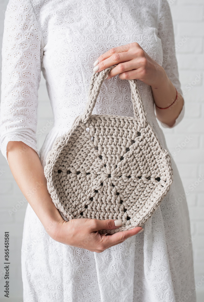 Woman holding beige knitted bag or purse in hands. Closeup Woman holding beige knitted bag or purse in hands. Closeup