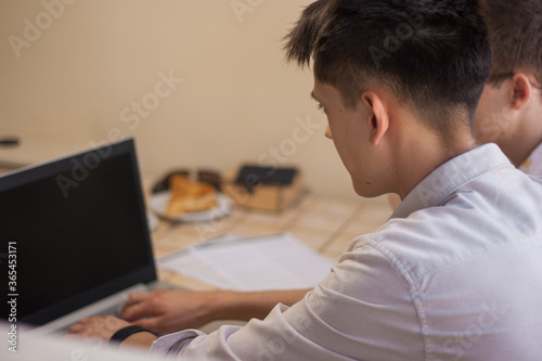 Young man looking into laptop and typing