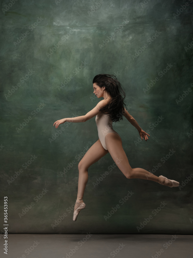 Coming on. Graceful classic ballerina dancing on dark studio background. Pastel bodysuit. The grace, artist, movement, action and motion concept. Looks weightless, flexible. Fashion, style.