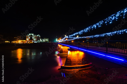Fototapeta Naklejka Na Ścianę i Meble -  Night city photographed at long exposure. Water, glare and night lights. Architecture and buildings of the city of Uzhgorod. Beautiful night photos without people. No one is on the street.