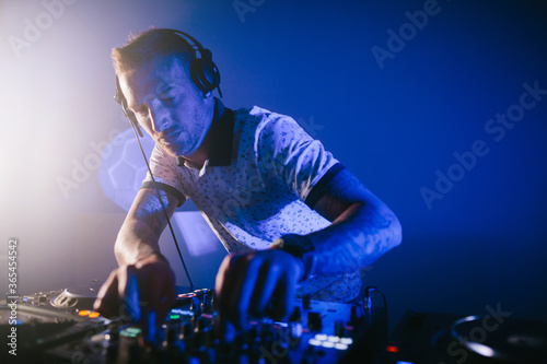 Obraz na plátně Techno young Caucasian male DJ with his mixer board playing music at a party