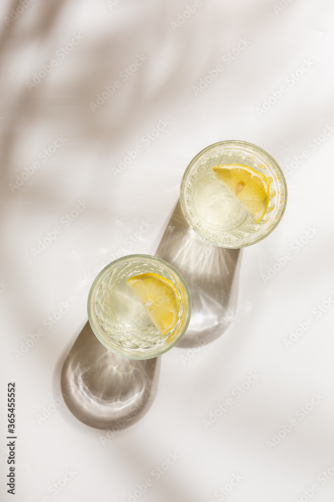 Summer tropical drink with a slice of orange. Bright sunlight with the shadow of palm tree Summer tropical drink with a slice of orange. Bright sunlight with the shadow of palm tree