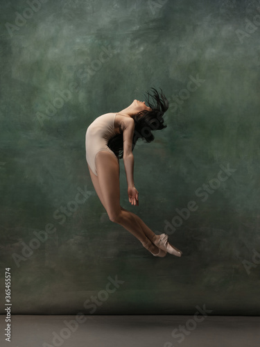 Freedom. Graceful classic ballerina dancing on dark studio background. Pastel bodysuit. The grace, artist, movement, action and motion concept. Looks weightless, flexible. Fashion, style.